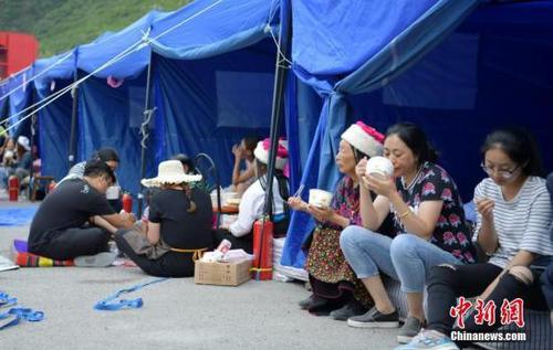 8月10日，四川九寨溝“8.8”地震震源中心附近的臨時安置點，受災(zāi)村民在帳篷邊吃飯。中新社記者 劉忠俊 攝