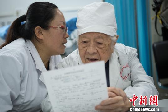 問診時，她的助手王利花趴在于載畿耳朵旁當“傳聲筒”，書寫病歷時，于載畿用尺子比著。　武俊杰 攝