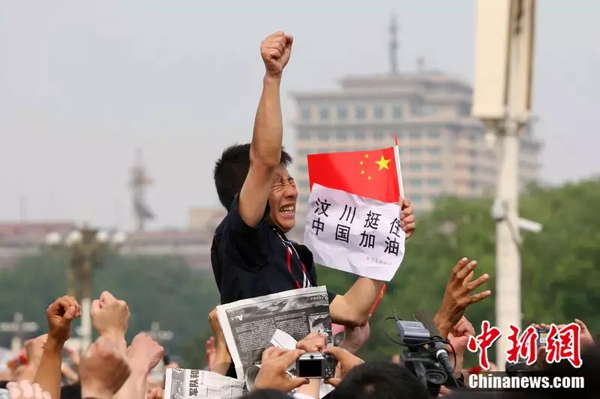 2008年5月19日，北京天安門廣場上的民眾為地震遇難者默哀，一位來自四川的男子高舉右手為家鄉加油。中新社記者 富田 攝